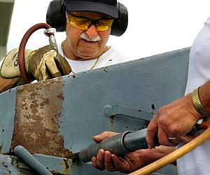 Volunteers scrape and paint one of the USS Slater's 40mm gun tubs